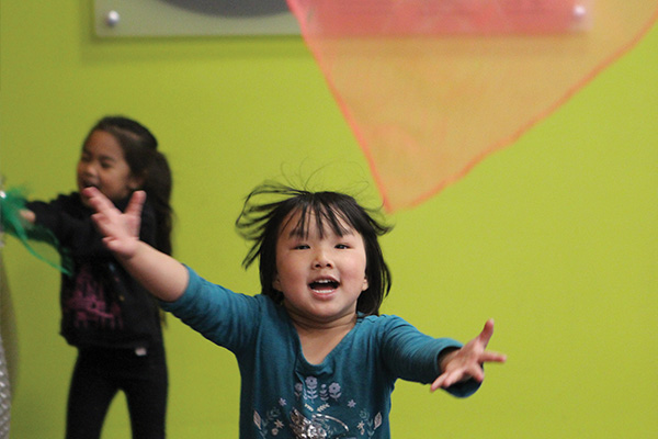 A little Asian girl runs forward with her hands outstretched.