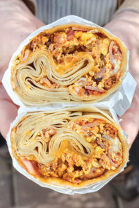 A burrito cut in half, held to show the insides.