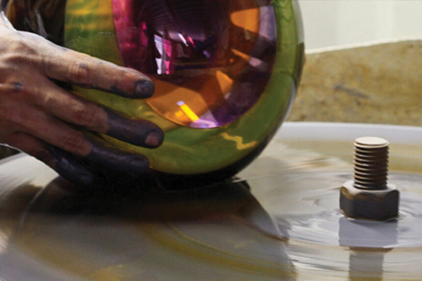 A hand is holding a piece of colorful blown glass.