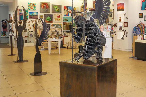 A room filled with art including sculptures on display and paintings on the wall.