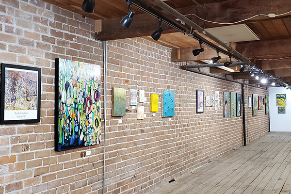 A brick wall covered in paintings.